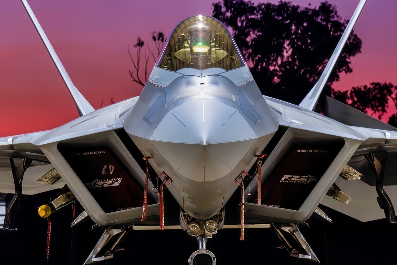 A U.S. Air Force F-22 Raptor assigned to the 199th Air Expeditionary Squadron sits beneath a hangar as the sun sets in Northern Territory, Australia, July 16, 2025, during Talisman Sabre 2025. Talisman Sabre is the largest bilateral military exercise between Australia and the United States advancing a free and open Indo-Pacific by strengthening relationships and interoperability among key allies and partners, while enhancing our collective capabilities to respond to a wide array of potential security concerns. (U.S. Air Force photo by Senior Airman Natalie Doan)