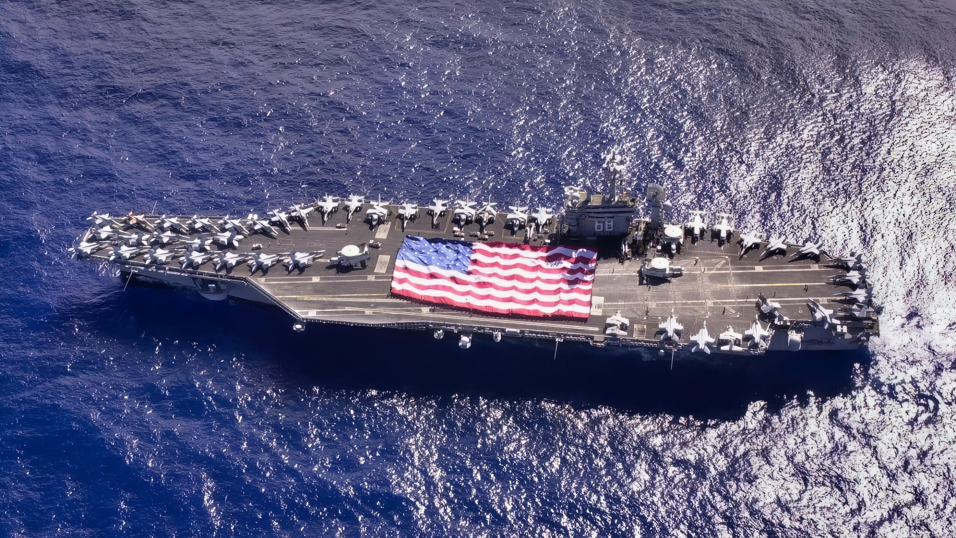 Pacific Ocean (Nov. 3, 2003) -- USS Nimitz (CVN 68) crewmembers participate in a flag unfurling rehearsal with the help of family and friends on the ship’s flight deck during a Tiger Cruise. The Nimitz Carrier Strike Group and embarked Carrier Air Wing Eleven (CVW-11) are en route to San Diego, Calif., following an eight-month deployment to the Arabian Gulf in support of Operation Iraqi Freedom. U.S. Navy photo by Photographer’s Mate 3rd Class Elizabeth Thompson. (RELEASED)