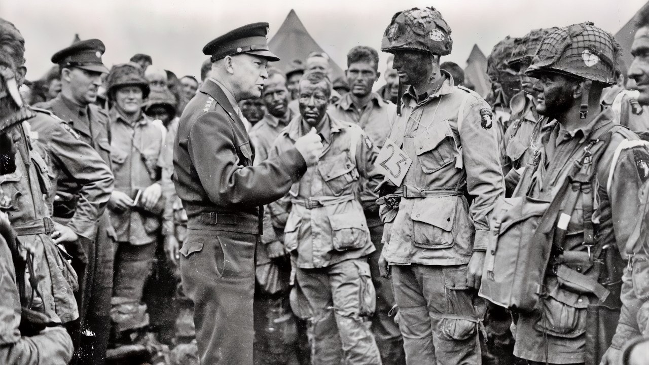 General Dwight D. Eisenhower addresses American paratroopers prior to D-Day. "Gen. Dwight D. Eisenhower gives the order of the Day. 'Full victory-nothing less' to paratroopers in England, just before they board their airplanes to participate in the first assault in the invasion of the continent of Europe." Eisenhower is meeting with US Co. E, 502nd Parachute Infantry Regiment (Strike) of the 101st Airborne Division, photo taken at Greenham Common Airfield in England about 8:30 p.m. on June 5, 1944. The General was talking about fly fishing with his men as he always did before a stressful operation (Eisenhower speaks with Hartsock).